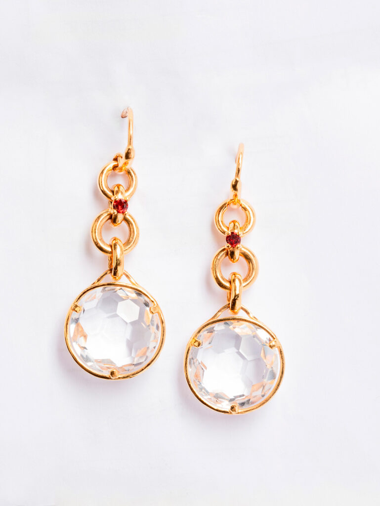 fotografia still-life gioielli artigianali siciliani coppia di orecchini in oro e cristallo con pietra rossa su sfondo bianco.
